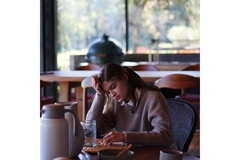 Image A young woman looks sad while sitting a table